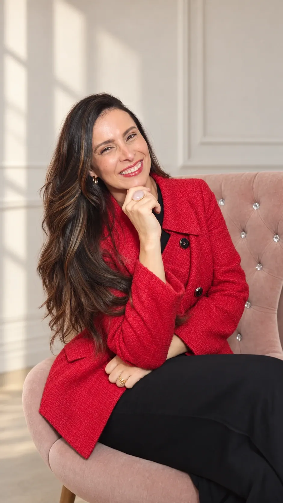 Alyne Osolins sentada, com blazer vermelho